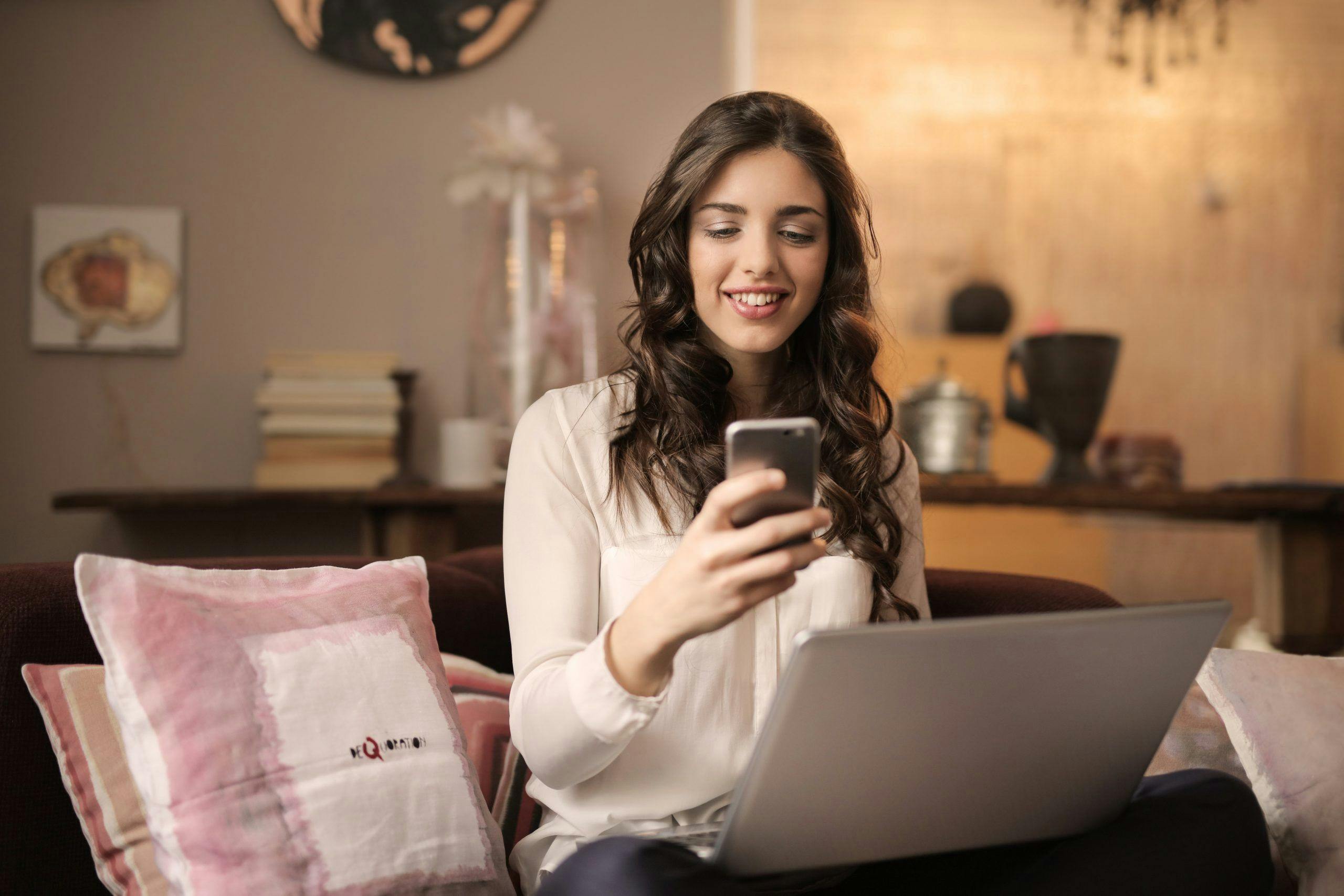 woman-sitting-on-sofa-while-looking-at-phone-with-laptop-on-920382-scaled-1.jpg